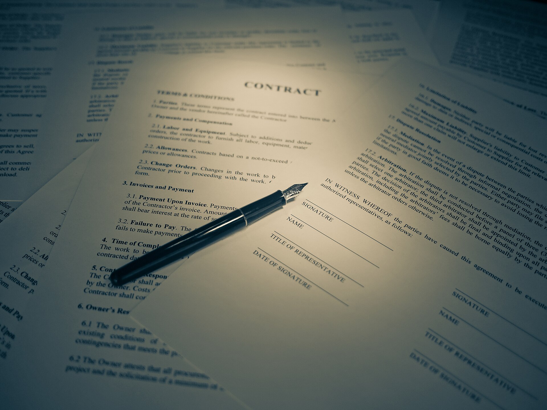 A contract on a desk with a pen laid across it, ready to be signed